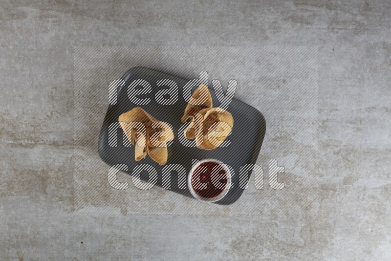 wonton cups with soy sauce ramkin on rectangle dark grey ceramic plate on grey textured counter top