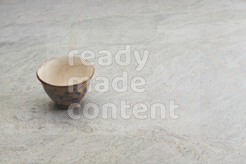 A multicolored pottery bowl on grey marble background