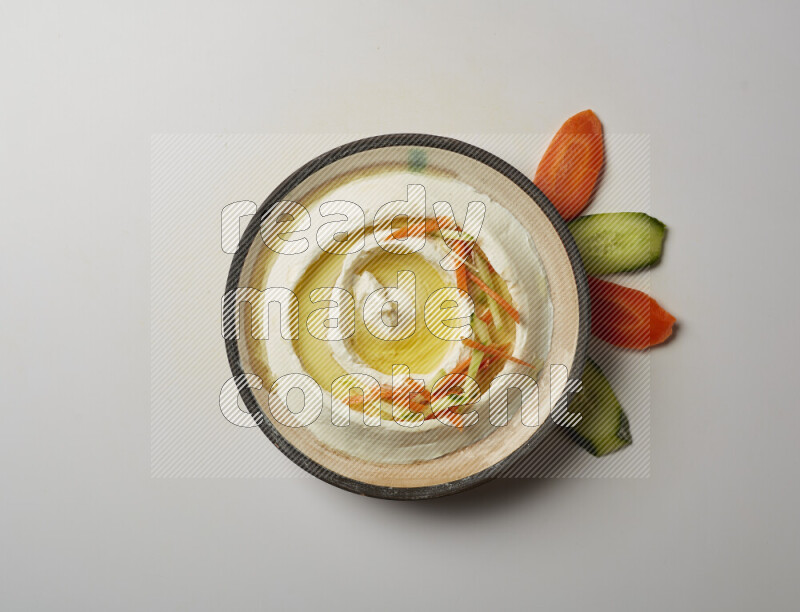 Lebnah garnished with sliced carrots &cucumber in a pottery plate on a white background