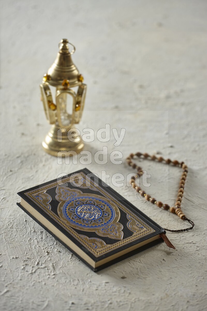 A golden lantern with different drinks, dates, nuts, prayer beads and quran on textured white background