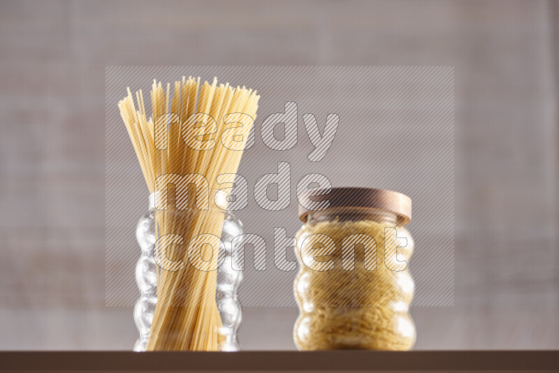 Raw pasta in glass jars on beige background