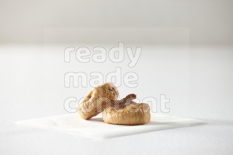 Two dried figs on a piece of paper on a white background in different angles