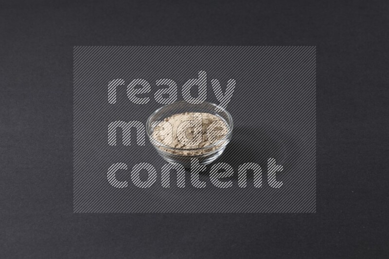 وعاء زجاجي ممتلئ ببودرة الثوم علي خلفية سوداء