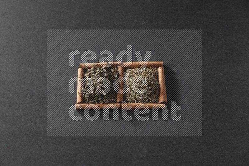 2 squares of cinnamon sticks full of cumin and dried basil on black flooring