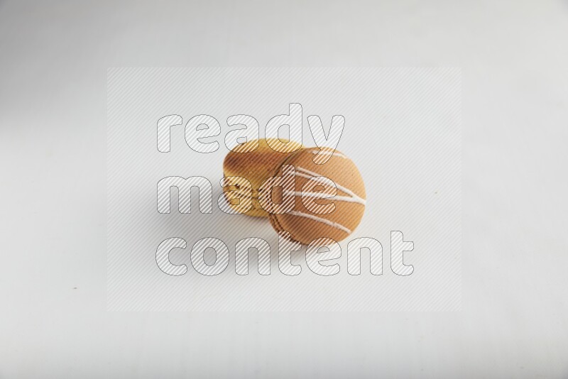 45º Shot of of two assorted Brown Irish Cream, and Yellow Crème Brulée macarons on white background