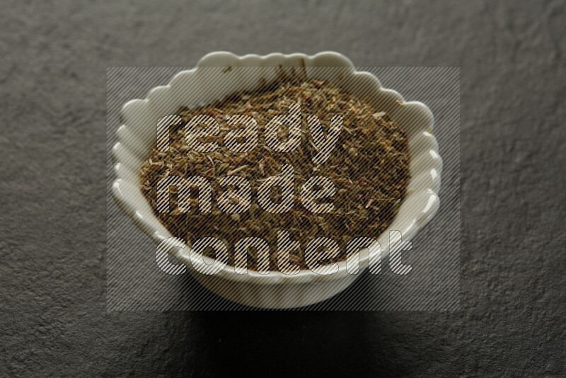wooden round sauce bowl filled with herbs on grey textured countertop