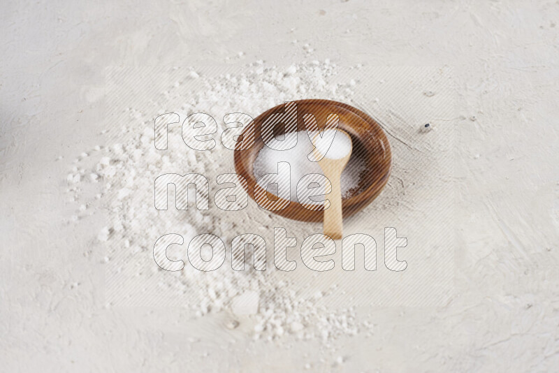 A pottery plate full of fine salt with bunch of coarse salt beside it on white background