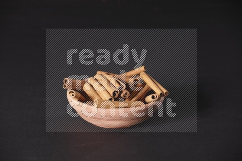 Cinnamon Sticks in a wooden bowl on black background
