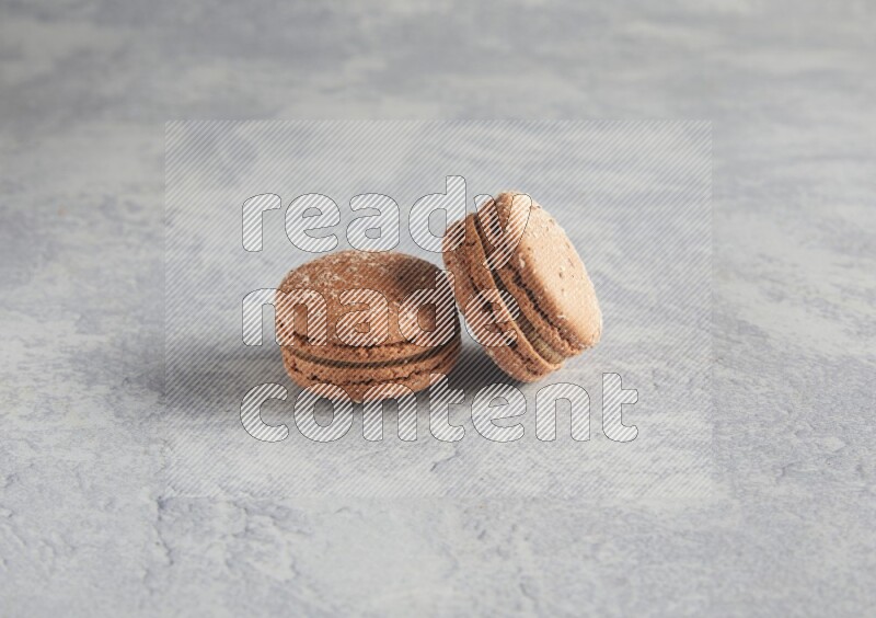 45º Shot of two Brown Hazelnuts macarons  on white  marble background
