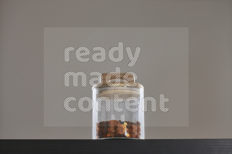 Sequins in a glass jar on black background