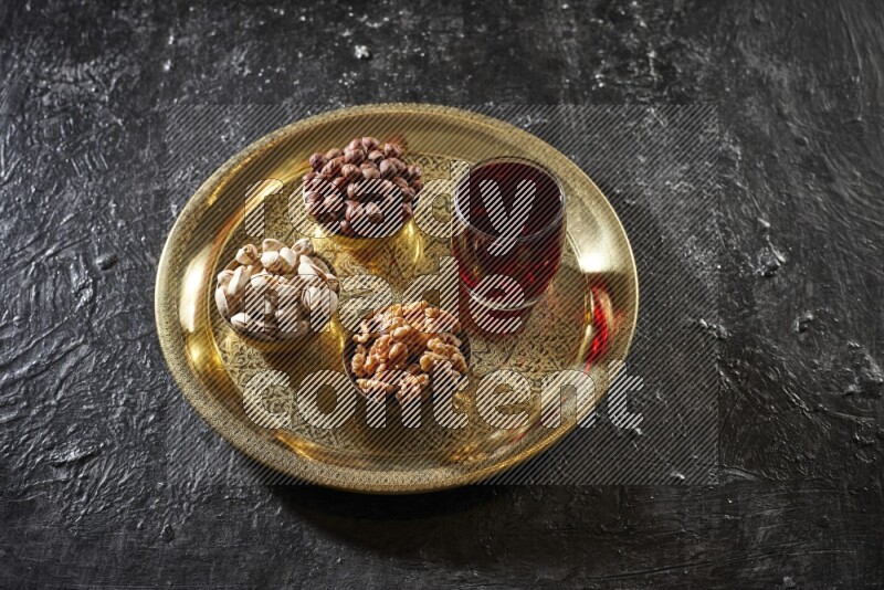 Nuts in metal bowls with Hibiscus on a tray in dark setup