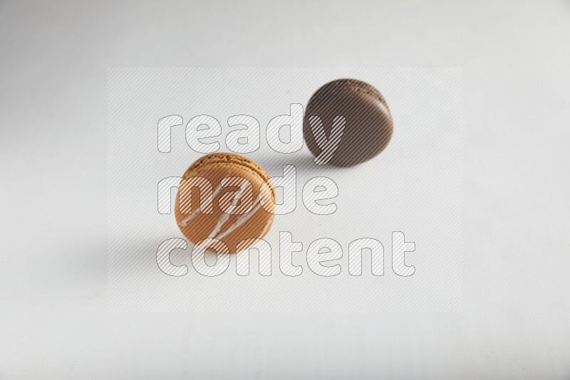 45º Shot of of two assorted Brown Irish Cream, and Brown Dark Chocolate macarons on white background