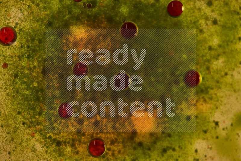 Close-ups of abstract red and green watercolor drops on oil Surface on green background