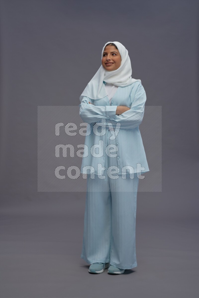 Saudi woman wearing hijab clothes standing with crossed arms on gray background