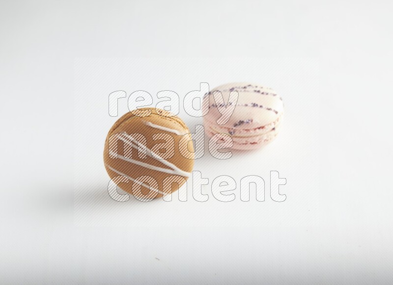 45º Shot of of two assorted Brown Irish Cream, and pink orange blossom macarons on white background