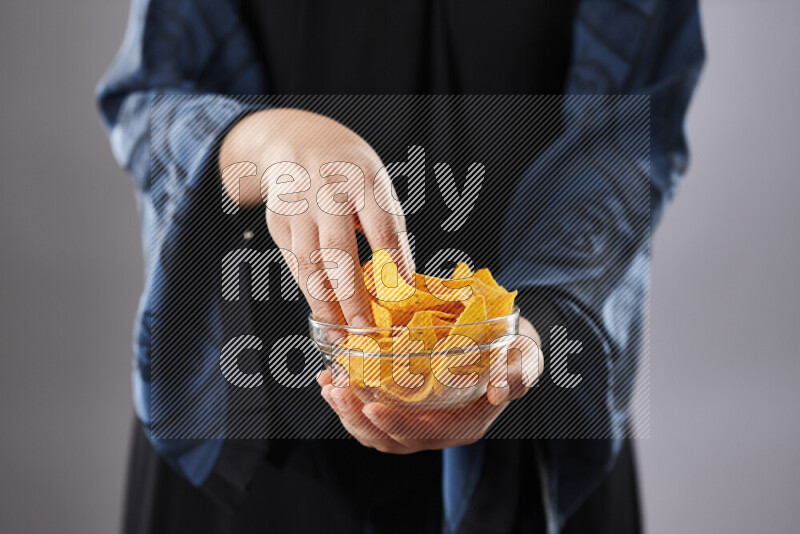 Woman in abaya holding different kinds of snacks in different positions