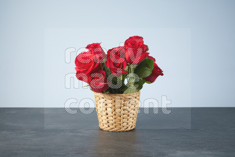 Vibrant red roses in a wicker basket on black marble background