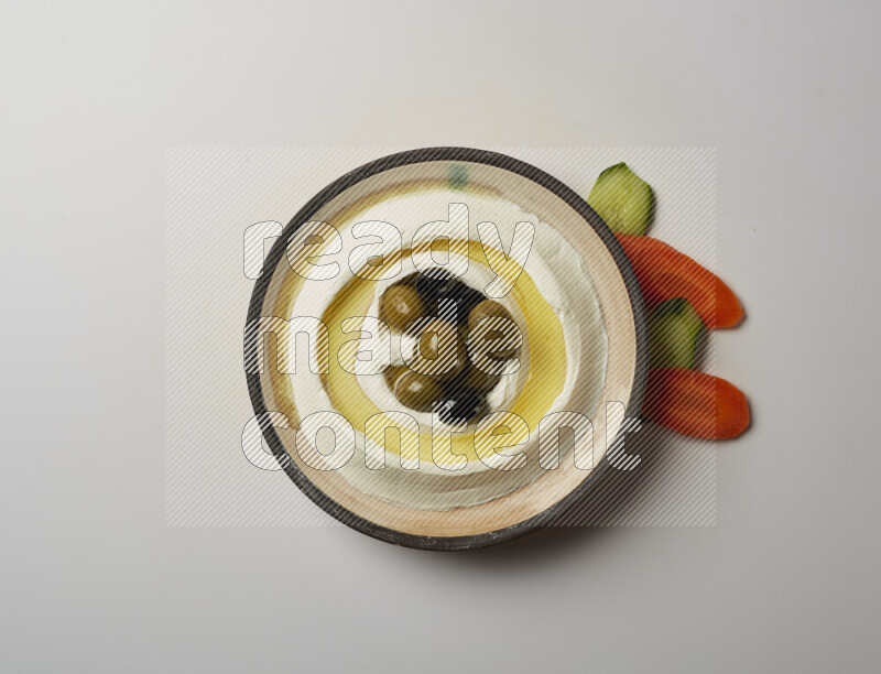 Lebnah garnished with whole black olives in a pottery plate on a white background