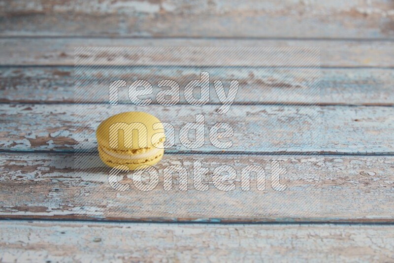 45º Shot of Yellow Lime macaron on light blue wooden background