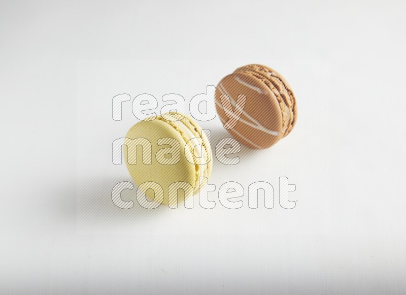 45º Shot of of two assorted Brown Irish Cream, and Yellow Lime macarons on white background