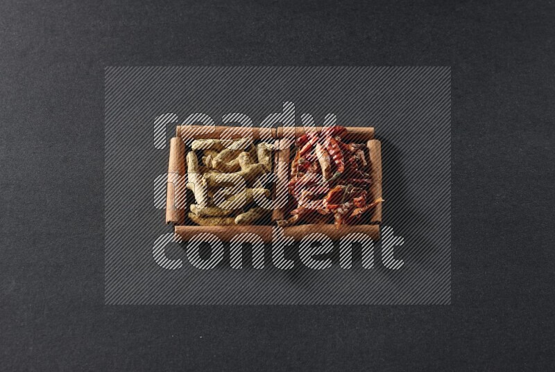 2 squares of cinnamon sticks full of chilis and turmeric fingers on black flooring