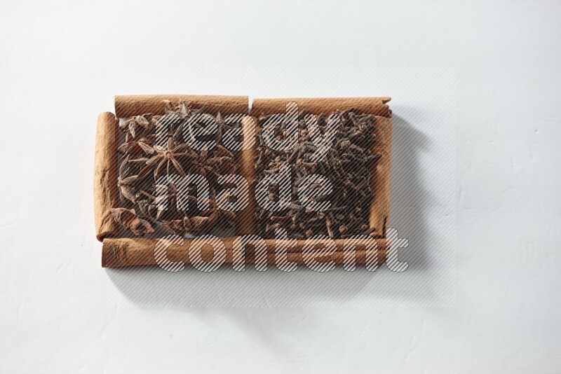 2 squares of cinnamon sticks full of cloves and star anise on white flooring