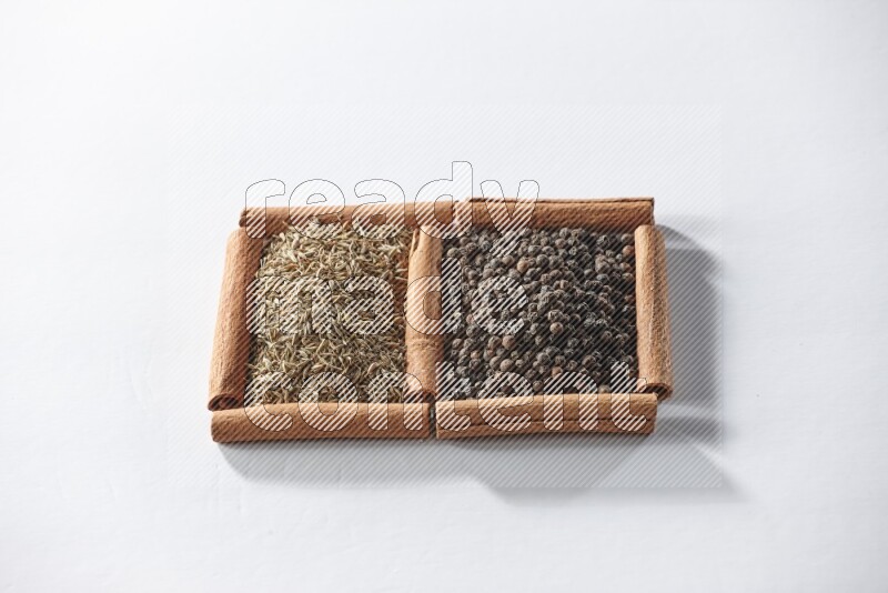 2 squares of cinnamon sticks full of black peppers and cumin on white flooring