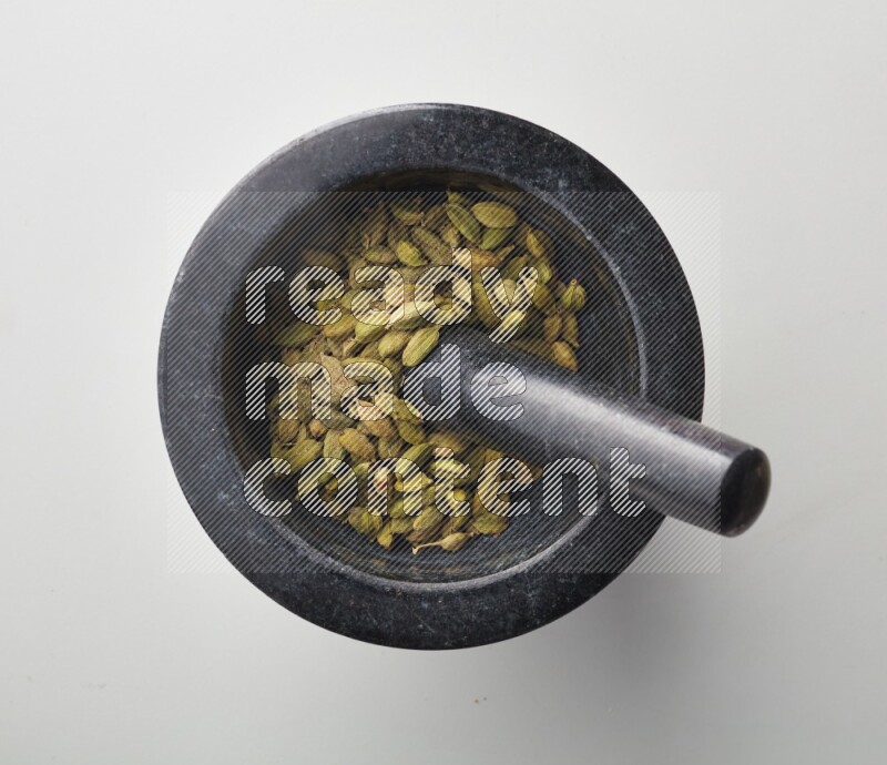 Top-view shot of Cardamon in herbs crusher on white background