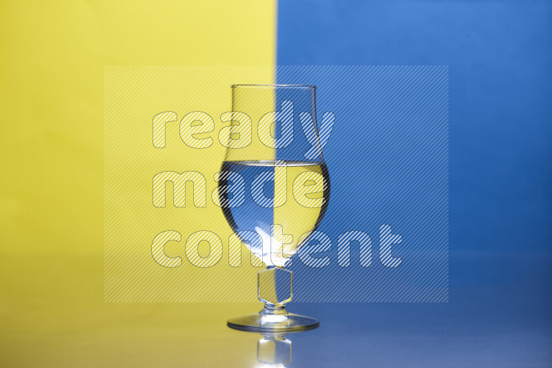 The image features a clear glassware filled with water, set against yellow and blue background