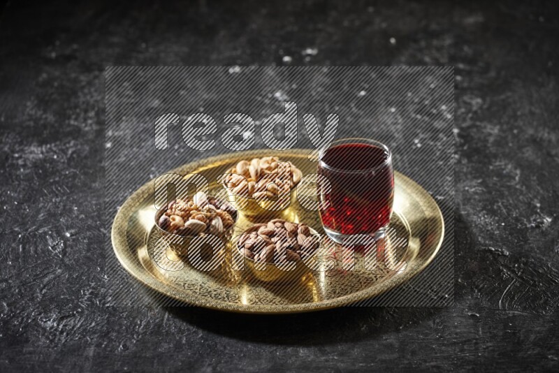 Nuts in metal bowls with Hibiscus on a tray in dark setup