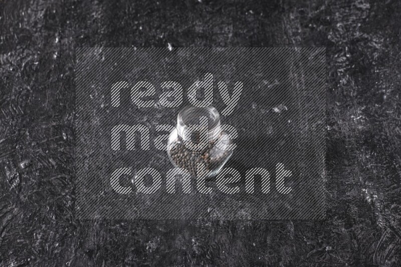 حبوب الفلفل الأسود في وعاء زجاجي علي خلفية سوداء