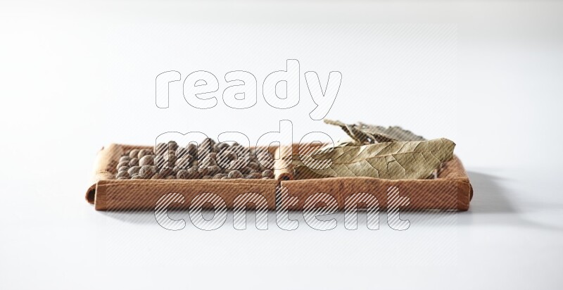 2 squares of cinnamon sticks full of allspice and bay laurel leaves on white flooring