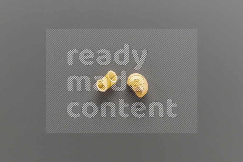 Elbow pasta with other types of pasta on grey background