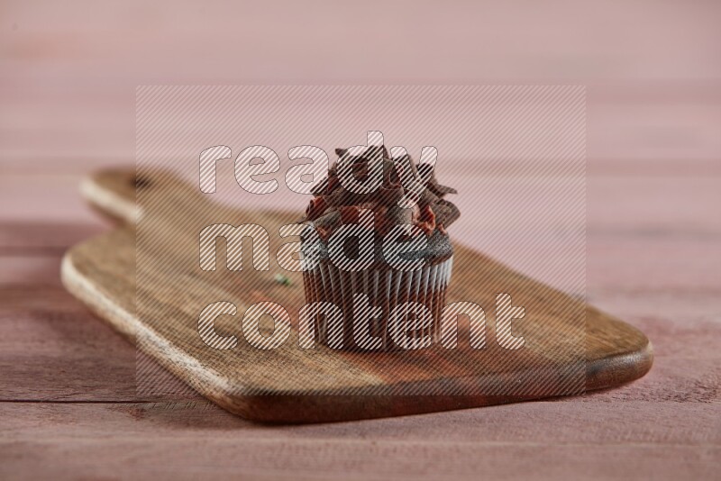 Chocolate mini cupcake topped with chocolate curls on a wooden board