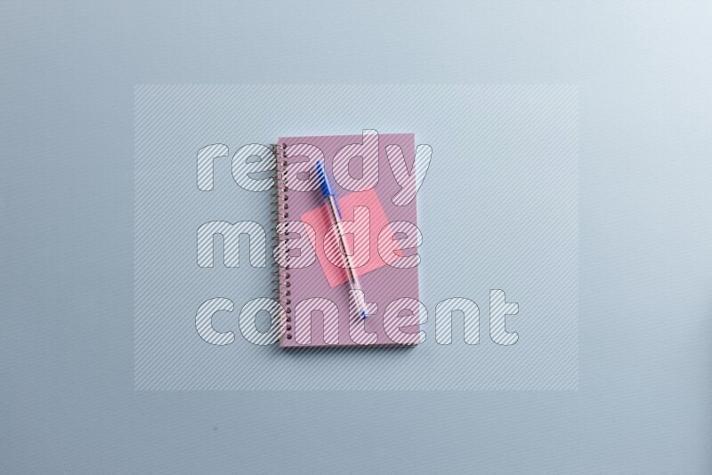 A purple notebook with different school supplies on blue background