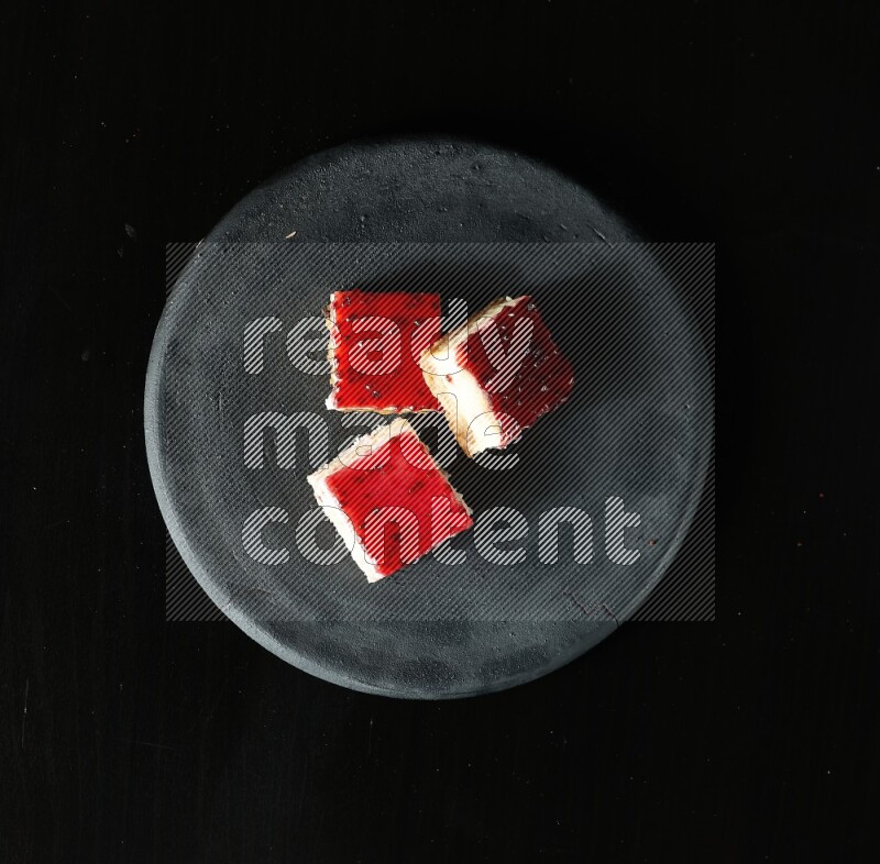 Assorted desserts in a black pottery plate on black background