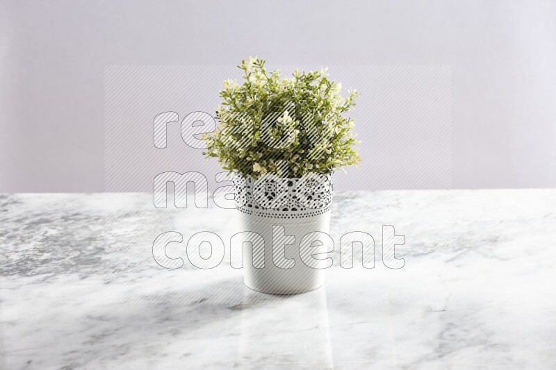 Artificial plant in white decorative pot on grey marble background