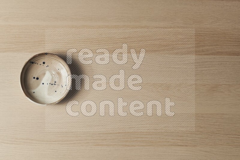 صحن فخاري متعدد الألوان على خلفية خشبية فاتحة