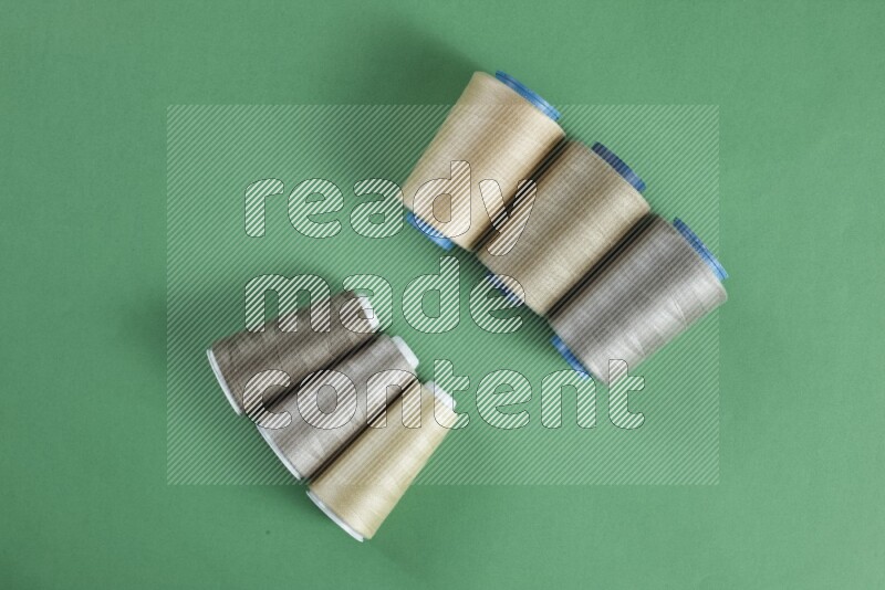 A brown collection of sewing and tailoring tools arranged on a green background