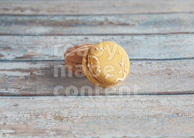 45º Shot of of two assorted Brown Irish Cream, and Yellow Piña Colada macarons on light blue background