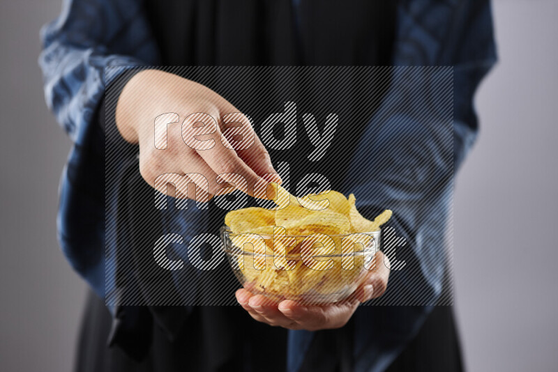 Woman in abaya holding different kinds of snacks in different positions