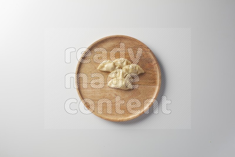 Five Sambosas on a wooden round plate on a white background