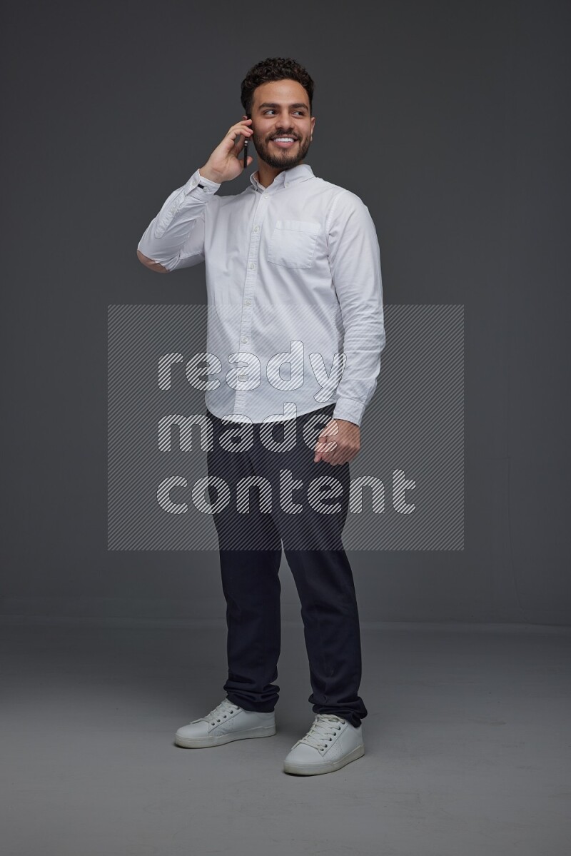 A man wearing smart casual talking in the phone eye level on a gray background