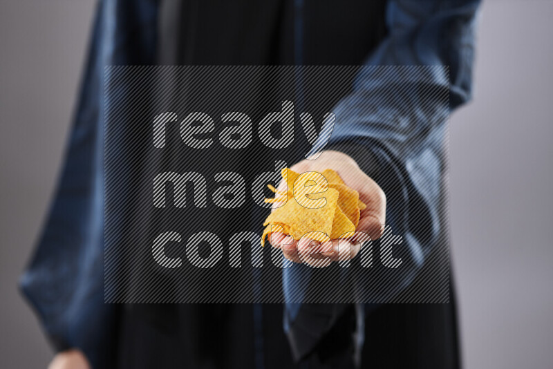 Woman in abaya holding different kinds of snacks in different positions