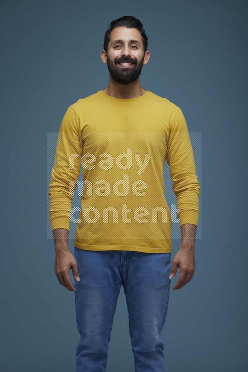 Man posing in a blue background wearing a yellow shirt