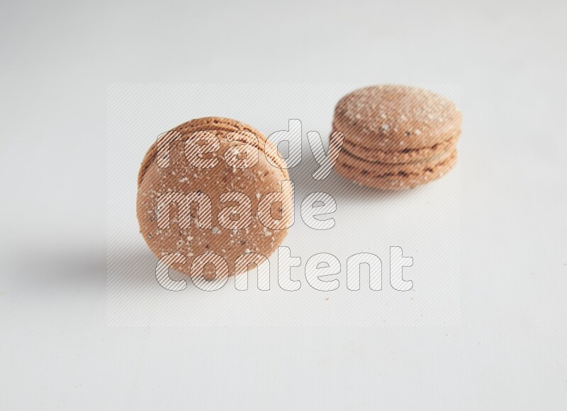 45º Shot of two Brown Hazelnuts macarons on white background