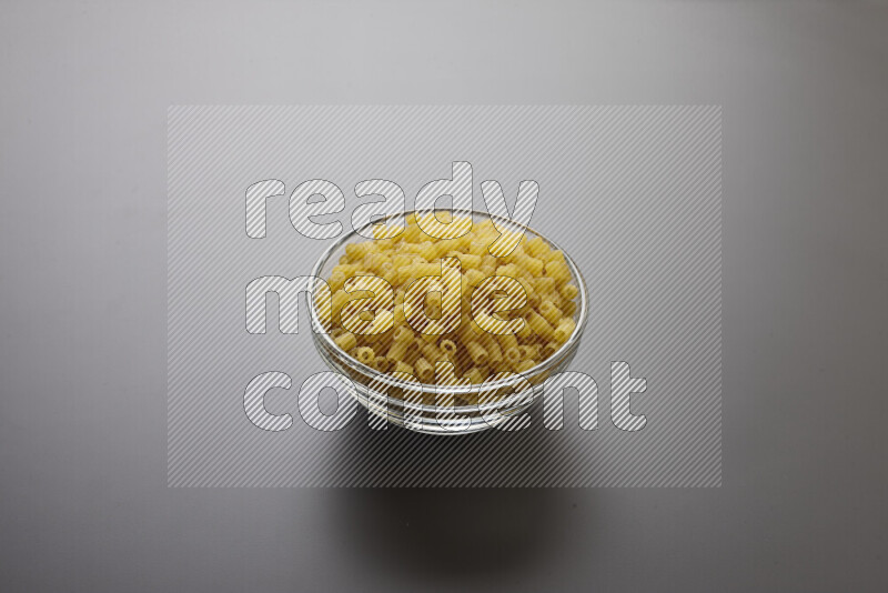 Small rings pasta in a glass bowl on grey background