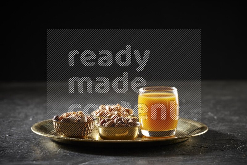 Nuts in metal bowls with qamar eldin on a tray in dark setup