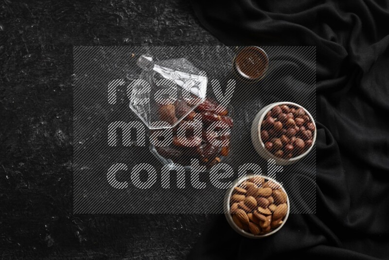 Dates in glass bowl with coffee and nuts in a dark setup