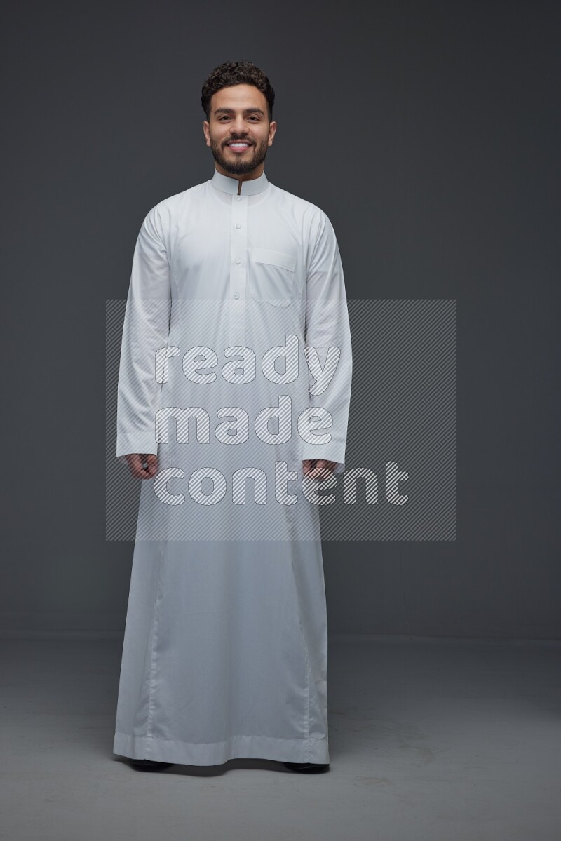 A Saudi man wearing Thobe standing and making different poses eye level on a gray background